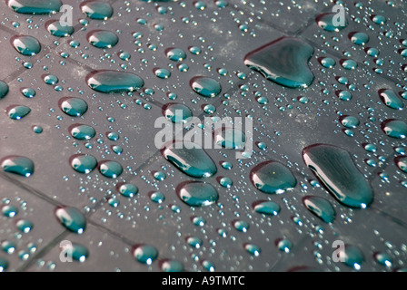 Abstract arrangement of rainwater shower creating droplets on grid marks on new plastic garden table outdoors in domestic back garden Essex England UK Stock Photo