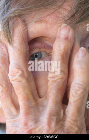 arthritic wrinkled hands of old woman hiding face Alzheimer Stock Photo