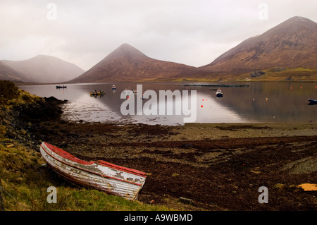 Isle of Skye - abandoned white and red boat on the shore of Loch Saplin with mountains in background Stock Photo