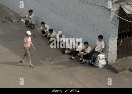 Restaurant workers having a break outside as a woman walks past, Datong, Shanxi, China. Stock Photo