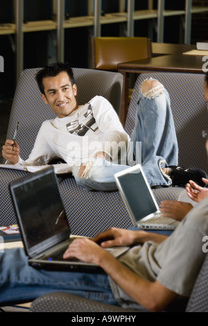 Students with laptop computers in library sitting on sofas studying Stock Photo