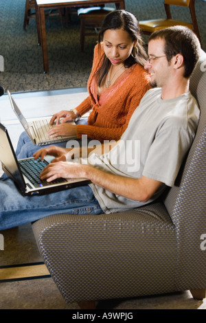 Students with laptop computers in library sitting on sofas studying Stock Photo