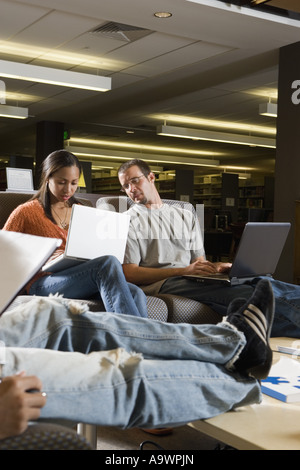 Students with laptop computers in library sitting on sofas studying Stock Photo