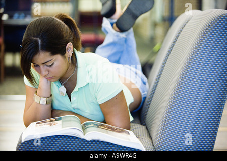 Young woman lying on the sofa reading a book Stock Photo