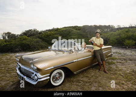 Young woman sitting in antique convertible car while man stands against the door Stock Photo