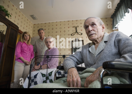 Adult children visiting and comforting senior parents in bedroom Stock Photo