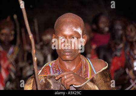 Lolgorian, Kenya. Siria Maasai Manyatta; newly shaved moran wearing ceremonial cowhide cloak looking sad and serious. Stock Photo