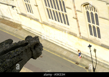 gargoyle from church tower is looking on the lonely girl, St Mary the Virgin, Church of Oxford, England, UK. Stock Photo