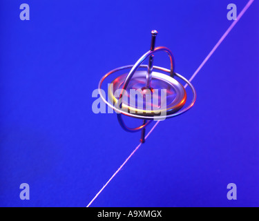 SPINNING GYROSCOPE BALANCES SUSPENDED ON STRING RED BACKGROUND Stock ...