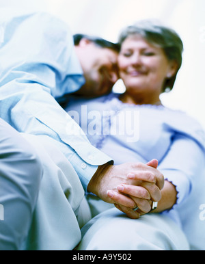 middle aged couple holding hands on sofa Stock Photo