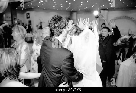 Poland, Lodz, bride with groom and wedding guests dancing in party (B&W) Stock Photo