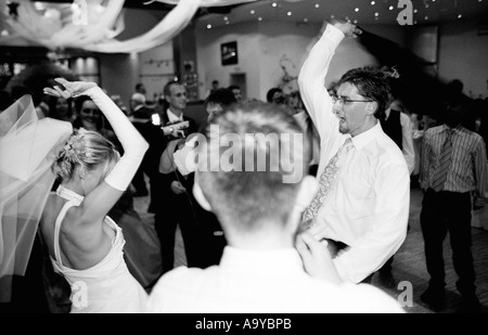 Poland, Lodz, bride with groom and wedding guests dancing in party (B&W) Stock Photo