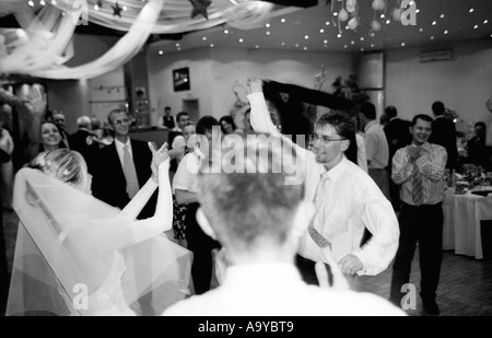 Poland, Lodz, bride with groom and wedding guests dancing in party (B&W) Stock Photo