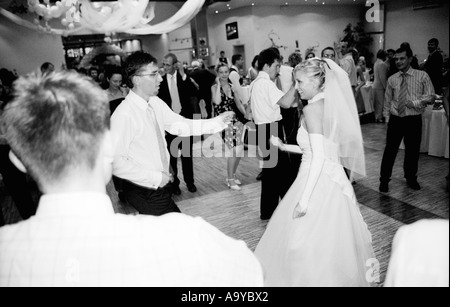 Poland, Lodz, bride with groom and wedding guests dancing at party (B&W) Stock Photo