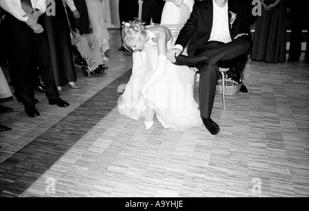 Poland, Lodz, bride and groom taking off shoes at wedding party (B&W) Stock Photo