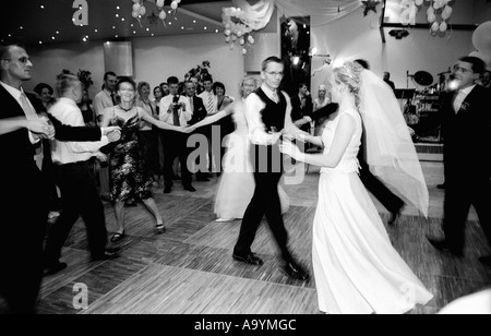 Poland, Lodz, bride and groom dancing with guests at wedding party (B&W) Stock Photo