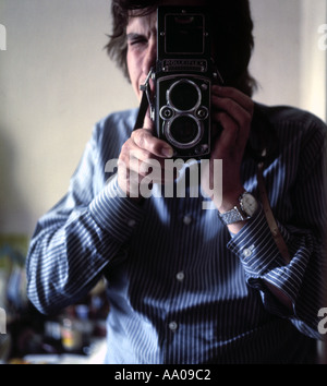 Man in a striped shirt taking a photograph with a classic Rolleiflex twin lens reflex camera in 1974 Stock Photo
