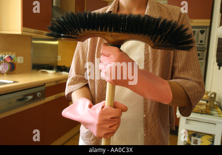 Woman in a kitchen holding a broom Stock Photo