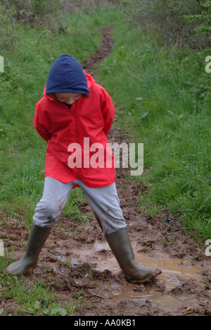 Young boy wearing red wellington boots palying in muddy stream Stock ...
