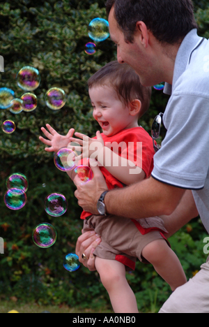 Father and son looking at bubbles and laughing Stock Photo