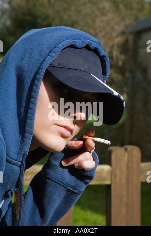 Young female smoking wearing a baseball cap and hooded sweatshirt Stock Photo