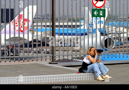 Girl watches aircraft through binoculars Schipol Airport Amsterdam spotter plane Stock Photo