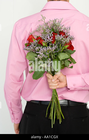 Man hiding flowers behind back Stock Photo