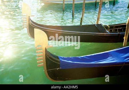 Italy, Venice, gondolas in sun on water surface Canale Grande Grand Canal, carved prows of gondolas moored by canal Stock Photo