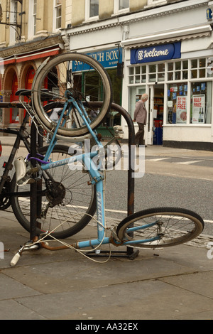 Bicycle parked in city urban bike parking rack but tipped up and damaged Stock Photo