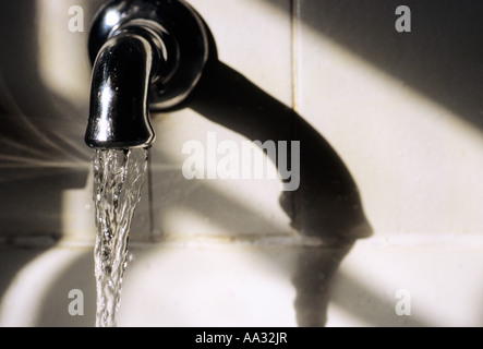 Bathroom faucet running water in a bathtub. Old plumbing fixture in a house. Stock Photo