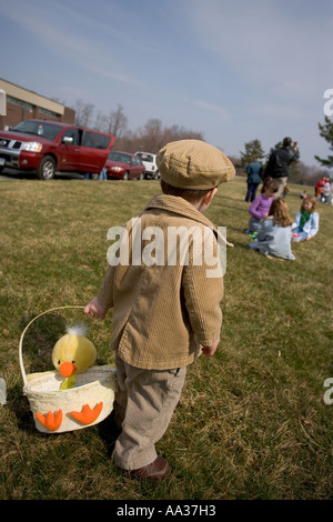 Easter Egg Hunt, small boy with irish hat and courdoroy jacket and basket looking for candy and treats Stock Photo