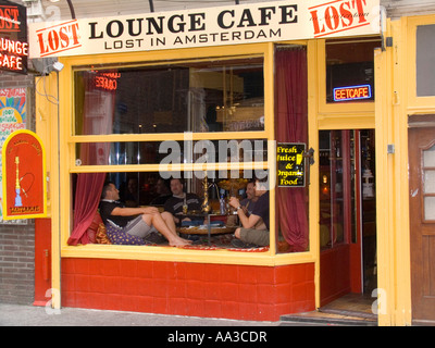 Young man holds water pipe while others relax in open window of Lost In Amsterdam lounge cafe Amsterdam The Netherlands Stock Photo