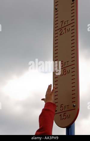 Young boy jumping and measuring the height of his jump on a ruler board Stock Photo