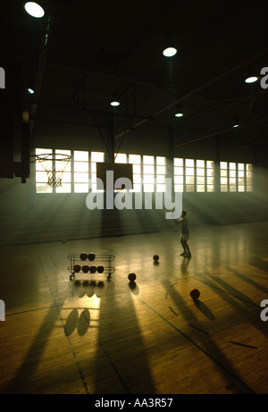 A high school basketball player spends extra time after a team practice Stock Photo