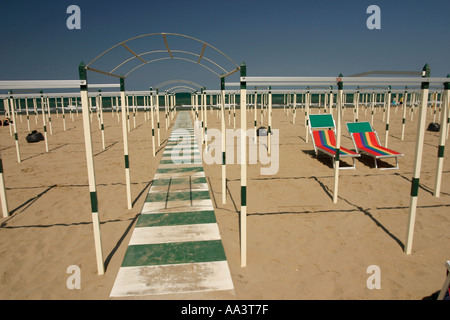 Riccione beach in Northern Italy Sectioned off by poles intersected by a green and white striped concrete walkway Stock Photo