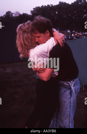 Young man and woman embrace in evening light on a camp site Stock Photo
