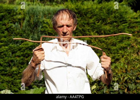 Water divining Man using copper divining rods to trace water flow England UK Stock Photo