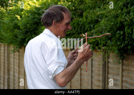 Water divining Man using copper divining rods to trace water flow England UK Stock Photo