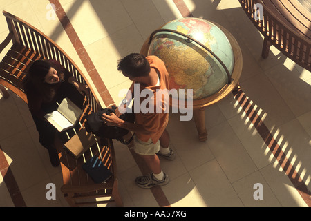 From overhead, two coed students can be seen talking over a class assignment in the school law library Stock Photo