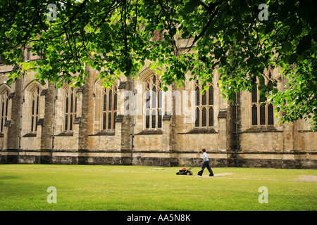 A LONE FIGURE CUTTING GRASS AT WINCHESTER CATHEDRAL AS THE SUN SHINES Stock Photo