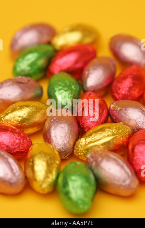 Bright vibrant colourful mini chocolate Easter eggs in foil wrappers on an orange background Stock Photo