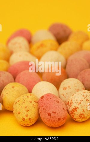 Brightly coloured seasonal traditional sugar coated mini chocolate confectionary Easter eggs with a Spring yellow background Stock Photo