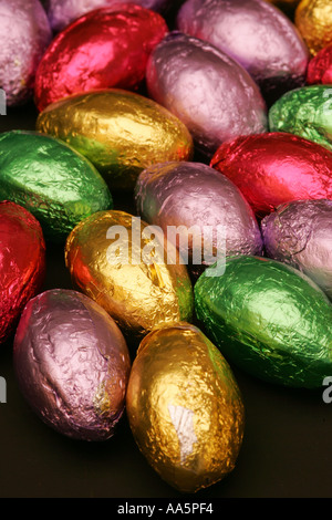Colourful bright foil wrapped mini chocolate seasonal Spring Easter eggs candy sweets confectionary striking black background Stock Photo