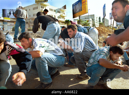 Palestinians duck after Israeli soldeirs fire rubber bullets and tear gas at them in the West Bank town of Ramallah Thursday Stock Photo