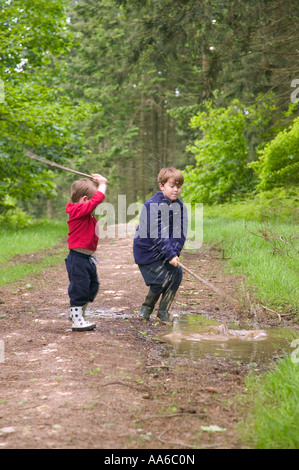 Two young brothers having fun splashing in a muddy puddle Stock Photo