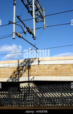 Detail of overhead powerlines at Crossflatts station with stone wall and shadows Stock Photo