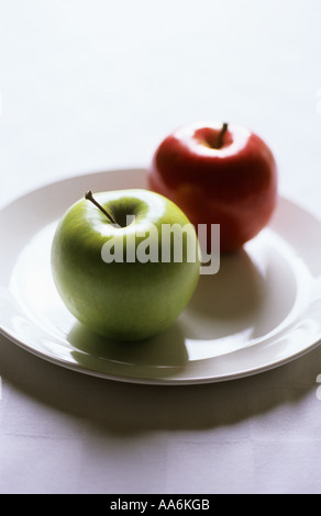 "red apple and green apple, white plate, focus on green" Stock Photo