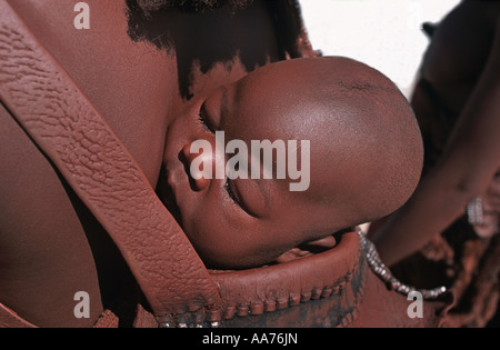 Himba baby held in a baby carrier on his mother s back Kaokoveld south of Opuwo Namibia Stock Photo