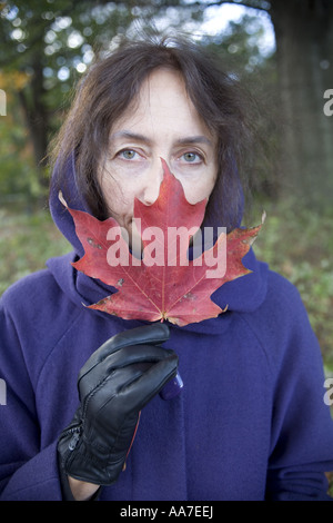 Portrait of woman holding autumn leaf in front of her face Stock Photo ...