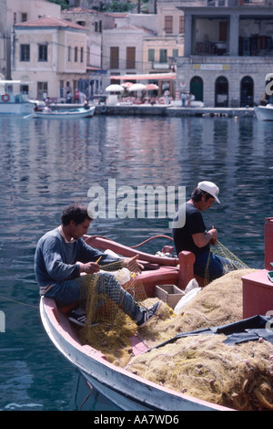 Fishermen mending nets in Symi harbour, Dodecanese Islands, near Rhodes, Greece Stock Photo